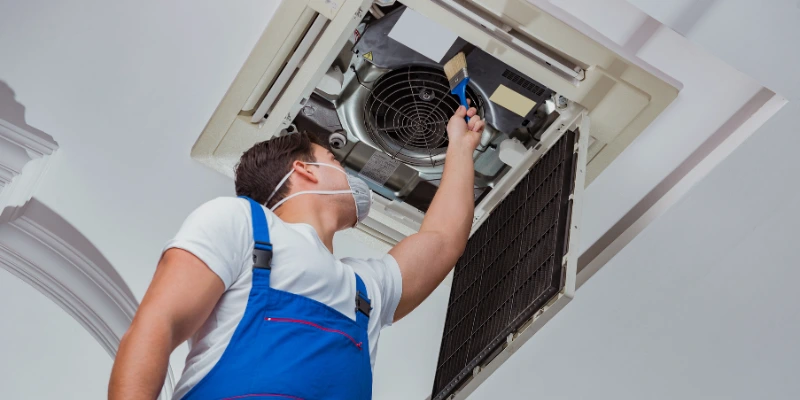 Técnico realizando mantenimiento preventivo a un sistema de aire acondicionado en un edificio comercial, asegurando su eficiencia y prolongando su vida útil.