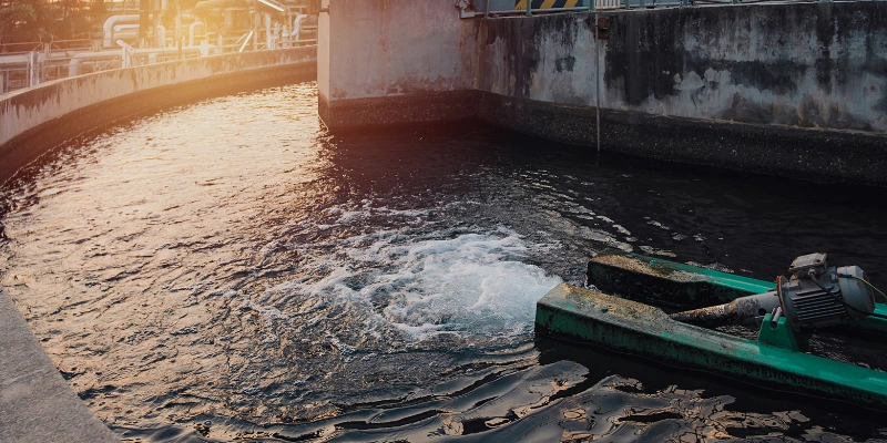 Vista cercana del proceso de tratamiento de aguas residuales en planta industrial al atardecer. Mantenimiento plantas aguas residuales