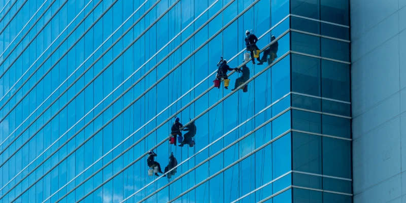 Técnico realizando limpieza de vidrios en altura con equipo profesional en edificio de oficinas en Costa Rica