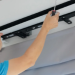 Errores al instalar aires acondicionados en oficinas. Técnico revisando unidad de aire acondicionado instalada en oficina corporativa