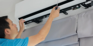 Errores al instalar aires acondicionados en oficinas. Técnico revisando unidad de aire acondicionado instalada en oficina corporativa