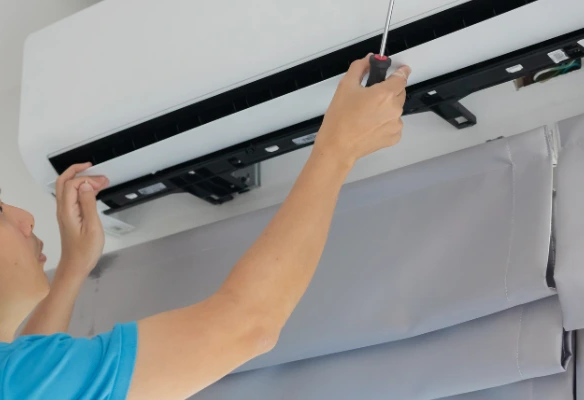 Errores al instalar aires acondicionados en oficinas. Técnico revisando unidad de aire acondicionado instalada en oficina corporativa