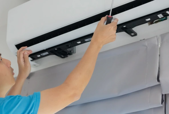 Errores al instalar aires acondicionados en oficinas. Técnico revisando unidad de aire acondicionado instalada en oficina corporativa